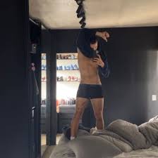 João Guilherme posa só de cueca em pé em cima da cama