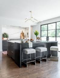 A Glass And Brass Cluster Light Illuminates A Black Breakfast Bar Seating Lucite Stools With Cowhide Seat Countertops Contemporary Kitchen Kitchen Inspirations