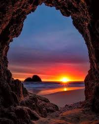 صورة لحظة غروب الشمس من قلب كهف عند الجبال صورة