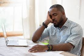 Homme Afro-américain Fatigué Tenant La Tête Dans La Main, Ressentant Un Manque  D'énergie, Dormant Devant L'ordinateur. Jeune Homme Noir Surchargé Épuisé  Ayant Une Pause Pendant Le Travail À Distance Ou Le Processus