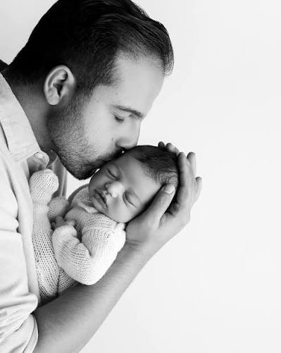 Black & White Fine Art Studio Family Photography — High-Key Monochrome Father Kissing Sleeping Newborn Head Portrait