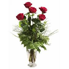 Un mazzo asciutto delle rose rosse e dei germogli rossi e verdi con neve bianca è su un fondo vago del cielo blu. Mazzo Di 5 Rose Fiorista Spagnoli