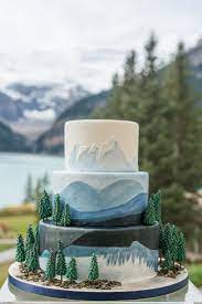 Fun Canadiana Style Nature Inspired Wedding Cake With Trees And Blue Hand Painted Mountains At Lake Louise P Nature Cake Mountain Wedding Cake Mountain Cake