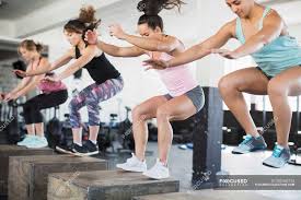 The squat motion is involved in most daily activities: Determined Women Doing Jump Squats On Boxes In Exercise Class Classmate People Stock Photo 202442724