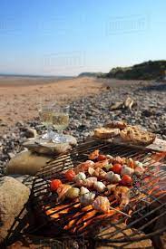 Fish skewers on a barbecue on a beach - Stock Photo - Dissolve