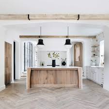 Modern kitchen with stainless steel hood suspended over white marble waterfall island with gas cooktop lined with piston barstools. Are Waterfall Countertops A Fad Plank And Pillow