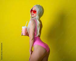Blonde with a beautiful big booty in a pink bathing suit drinks a drink.  Girl in