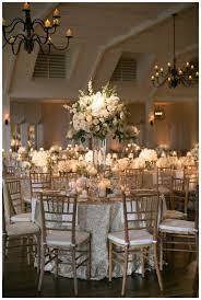 Gold Ivory And White Wedding Reception Decor With White Florals In Glass Vessels Plac White Wedding Decorations Wedding Table Linens Wedding Reception Chairs