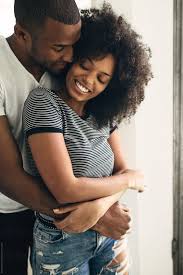 Homme essayant de mordre quelque chose et sa collègue rire durement. Young Black Couple Embracing At Home By Bonninstudio