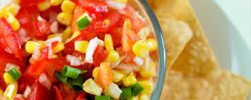 Close-up of a food processor pulsing fresh tomatoes into a chunky salsa recipe