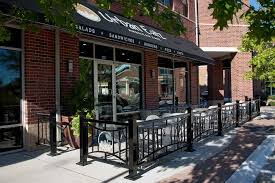 Outdoor Cafe Seating With Metal Fencing Depicting The Logo Of The Business