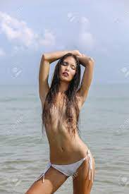 Fashion Sexy Beautiful Asian Girl In Bikini Without Bra, Closes A Breast  With Hair, Against The Sea Background. Summer Holidays, Vacation On A  Tropical Island. Vogue Style. Stock Photo, Picture and Royalty