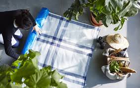 A Woman Rolling Up A Picnic Blanket Made From Ikea Blue Bags And Tea Towels Ikea Hack Creative Hacks Ikea