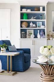 Blue living room with a large framed artwork and tufted chairs accompanied by glass top tables. 17 Blue Living Room Decor Ideas Sebring Design Build