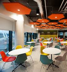 This Bright And Colourful Workplace Cafe Uses White Cafe Tables With Orange Chairs Yellow Cha Cafeteria Design Office Cafeteria Design Corporate Office Design