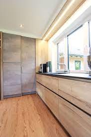 kuche mit eingefraster led beleuchtung uber dem fenster beton look kombiniert mit holz dekor und schwarzer natursteinar kuche beton led beleuchtung beton look