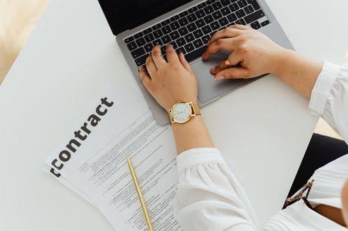 Person Holding a Document while Using Laptop · Free Stock Photo