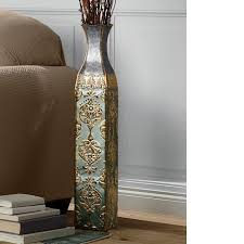 Formed from strong metal, the elegant accent piece boasts a rich gold finish with subtle distressing. Reflections Metal Floor Vase Seventh Avenue