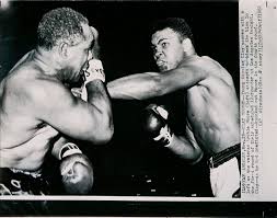 Young Cassius Clay scores with a left against the veteran Archie Moore in  the first round of the fight in Los Angeles