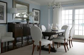 Sophisticated dining room boasts gray damask dining chairs placed around a dark stained dining table illuminated by a crystal chandelier hung over the table and reflected in a gray mirror mounted above a gray buffet table topped with glass buffet lamps lighting an ivory wall accented with decorative molding. Dining Room Buffet Table With Mirror Novocom Top