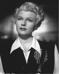 Rita Hayworth. For those that may question this, Rita bleached her hair  blonde when she appeared in the 1947 film The Lady From Shanghai. Beautiful  coat/gown but those sandals! are something else.