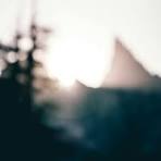 A blurry photo of the sun setting behind a building photo ...