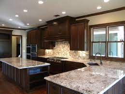 The black speckled polished granite countertops match with the dark paneled wood cabinets and drawers; Bianco Antico Granite With Dark Cabinets Kitchen Remodel Kitchen Design Kitchen Remodel Small