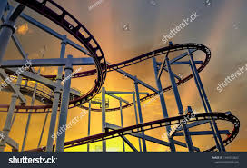 A genuine physical bitcoin with roller coaster in background to illustrate the up and down nature and volatility. Steel Rails For Driving Roller Coasters In Circular Motions On Background Evening Sky And Sun Shining Concept Relaxation And Holi Roller Coaster Roller Rails