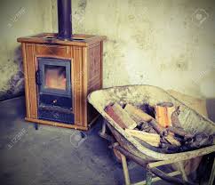 Ancient Tiled Stove And Wheelbarrow Full Of Firewood To Heat