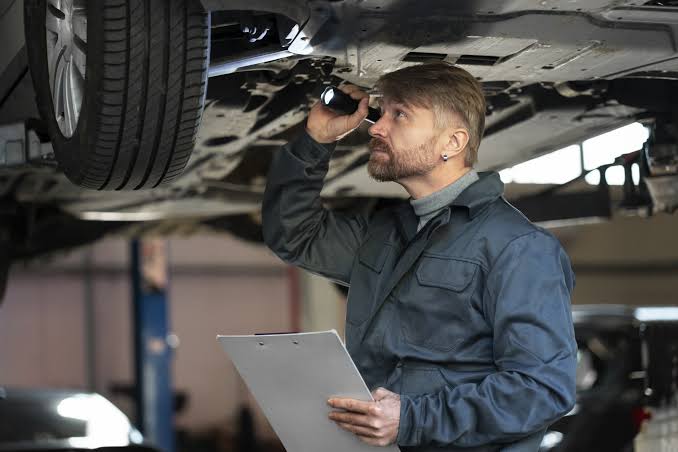 Mechanic inspecting the underbody, suspension and tyres of a used car before purchase.|Arabwheels.ae