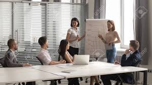 two diverse female coaches team give flip chart presentation