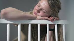 Tired Mother At The Baby's Crib.