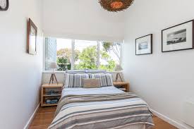 The beach house guest bedroom has a double bed, two twin beds, and a window with an ocean view. Serene Beach House Taken Over By Coastal Beauty