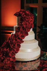 White Five Layer Wedding Cake With Gold Banding And Crimson Red Roses Cascading Down Layers Wedding Cake Red Red Velvet Wedding Cake Red Cake