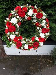 The importance of funeral flowers is what we take the most pride in. Wreath In Reds And Whites On A Stand Wreaths Funeral Arrangements Flower Arrangements