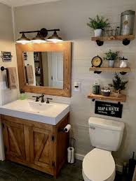 Rustic bathroom decor provides contrast to the warm, creamy walls, bronze mirror frame, and orchid on the countertop near the sink. Rustic Bathroom Decoration Small Farmhouse Bathroom Small Apartment Bathroom Bathroom Design