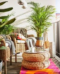 Deux Fauteuils En Rotin Deux Poufs Empiles Pour Faire Une Table Des Plantes Et Des Tapis De Couleur Disposes Sur Un Balcon Idee Deco Deco Et Deco Balcon