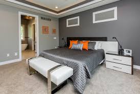 Grey and orange accents in simple and elegant bedroom with king size bed and painting on the empty concrete wall, real photo. Dark Grey Accent Wall Houzz