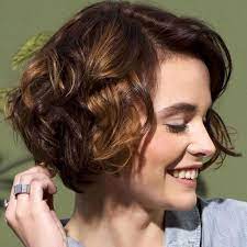 Smiling Young Woman Head Turned To One Side Wearing A Curled Bob With Deep Side Part Short Hair Thin Hair Short Haircuts Fine Hair Hairstyles For Thin Hair