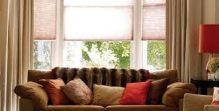 Soft sheers on a rustic iron rod hang over woven grass shades and gently filter light into the room. Bay Window Solutions
