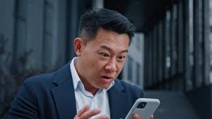 Happy shocked amazed satisfied successful winner Asian 40s middle-aged man  outdoors win with mobile phone online bet business victory offer prize  winning financial growth with smartphone wow reaction
