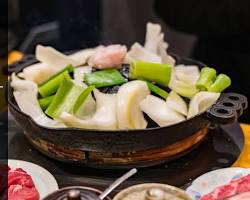 ジンギスカン：ジンギスカン鍋で焼かれる羊肉と野菜の画像