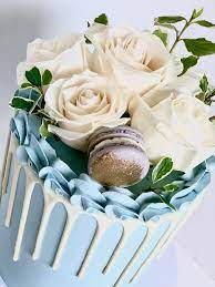 Baby Shower Blue Cake Featuring White Blooms And White Drip Blue Birthday Cakes Baby Shower Cakes For Boys Blue Baby Shower Cake