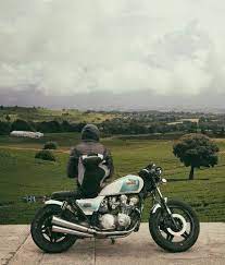 Man Sitting On Motorcycle While Facing Broad Green Field Motorcycle Pictures Travel Visa Motorcycle