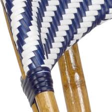 A white rattan chair with green floral cushions sits in a sunroom in front of a rattan tiki bar matched with wicker backless stools and placed in front of beadboard trim. Sienna Coastal Beach Blue And White Woven Rattan Counter Stool Kathy Kuo Home