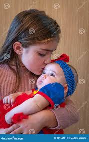 Little Girl Holds Her Baby Sister in Her Arms Stock Image
