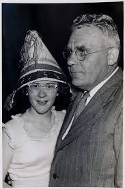 woman wearing hat and glasses and and man in glasses "Nancy, Queen of  Carnival