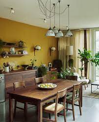 At the left of the picture, there is a distressed, painted metal locker — a mix of dark grey and rusty brown. Kitchen With Recycled Wooden Cabinets And Mustard Yellow Wall In 2021 Dining Room Wall Color Yellow Dining Room Rustic Dining Room