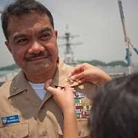 Chief Hospital Corpsman Jonathan Kitchen receives his combination cover  from his son and daughter at a chief petty officer pinning ceremony.