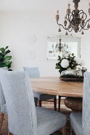 Under a navy blue balcony awning, navy blue basketweave chairs with matching stools are topped with blue stripe lumbar pillows and navy blue basketweave dining chairs surround a white dining table. French Country Dining Room Oh Sweet Basil